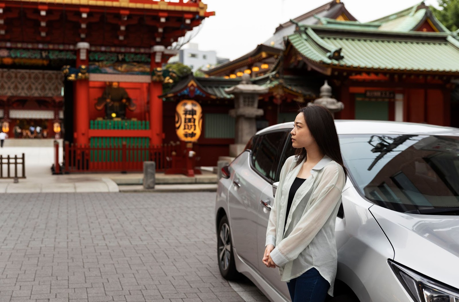 A woman standing by her car, contemplating where to go after getting a Japanese driver's license