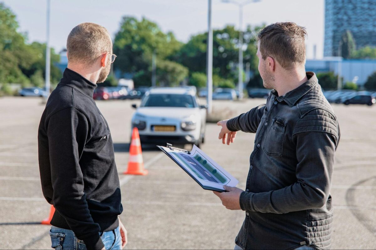 Driving camp instructor pointing out mistake to foreign student