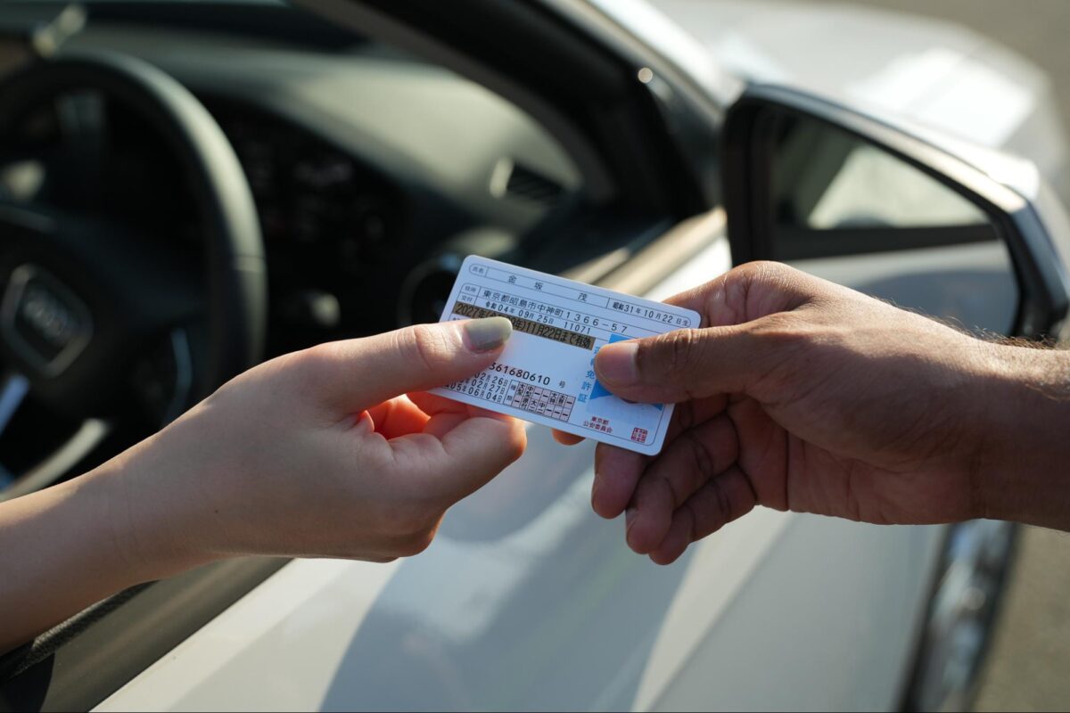 A Japanese license being handed over from a car