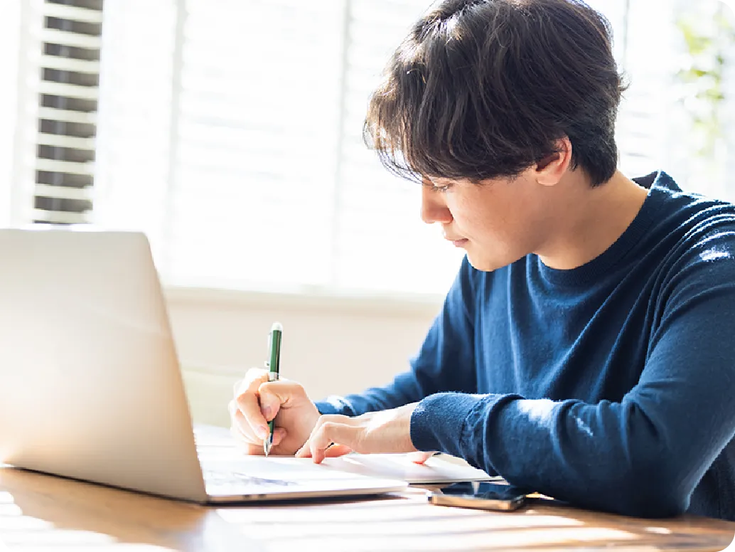 机に向かい勉強をする男性